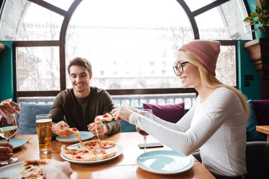People smiling and eating in a restaurant.
