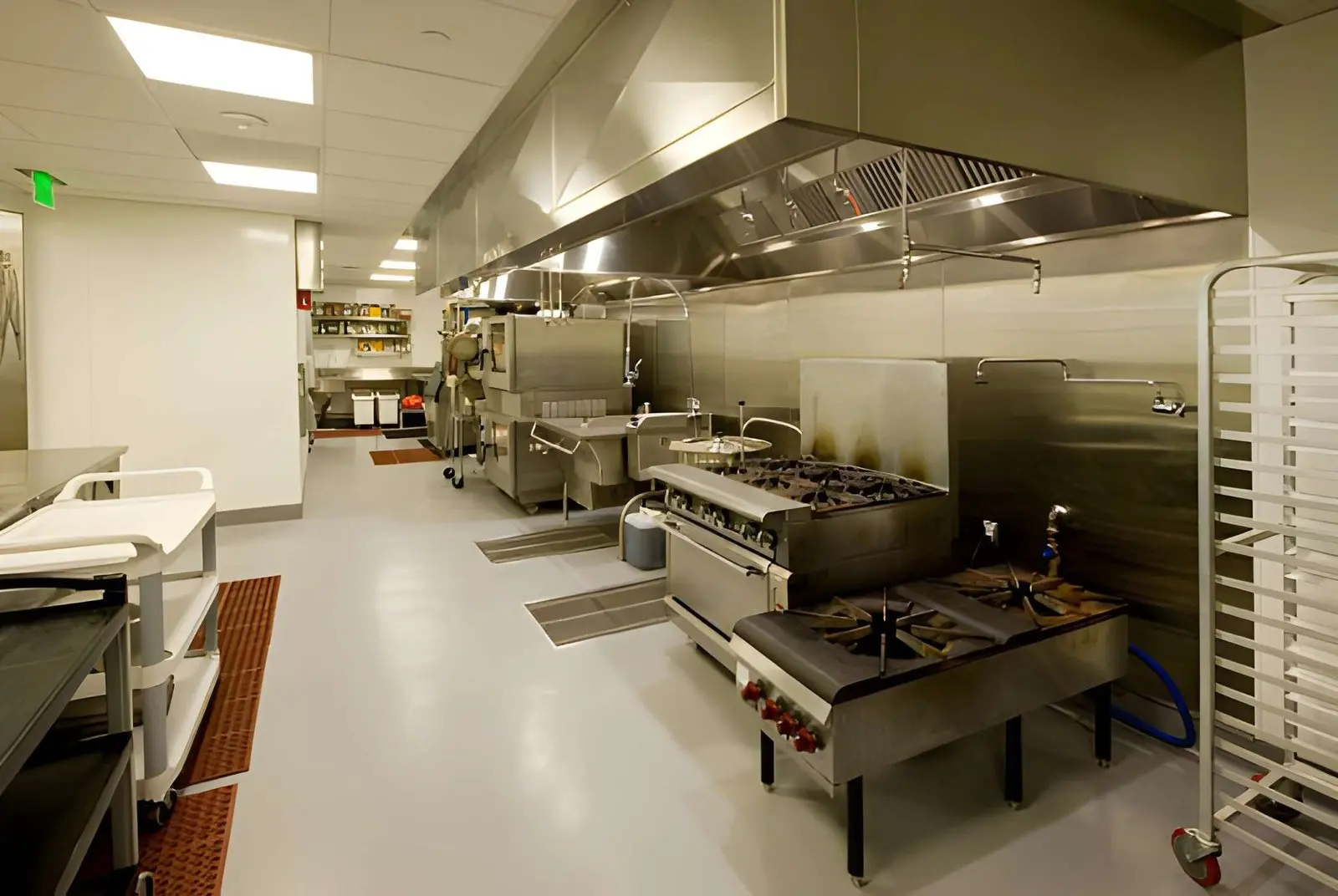 Technician performing Commercial Exhaust Hood Repair in busy commercial kitchen ventilation system